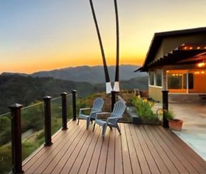 Los Angeles house for rent - A wooden deck with two chairs and a table overlooking a mountain range at sunset.