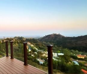 Los Angeles house for rent - A wooden railing overlooks a town and a hill with a building on top.