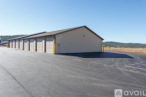 Summerset apartment for rent - A large, grey, single-story building with a garage door is situated in a parking lot.