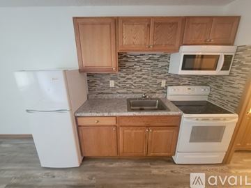 La Crosse apartment for rent - A kitchen with a white refrigerator, white oven, and brown cabinets.