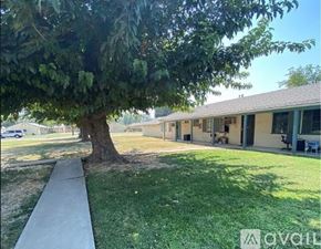 Merced apartment for rent - A tree is in front of a building with a walkway in front of it.