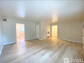 Merced apartment for rent - A spacious room with wooden flooring and white walls.