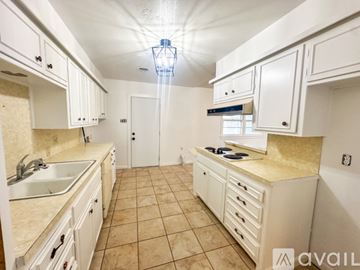Lubbock house for rent - A kitchen with white cabinets and a beige countertop.