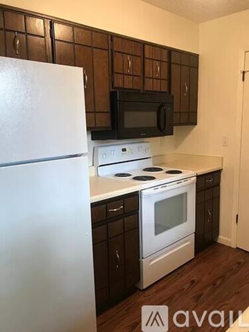 Longmont apartment for rent - A kitchen with a white refrigerator, black microwave, and white stove top oven.