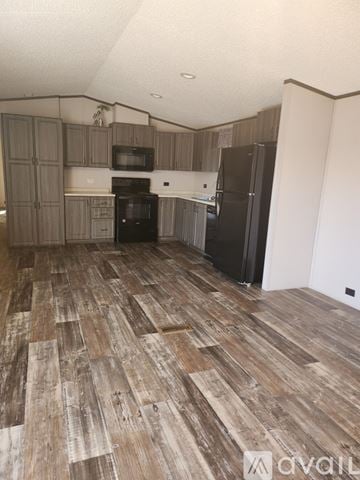 Odessa house for rent - A kitchen with wooden flooring and a black fridge.