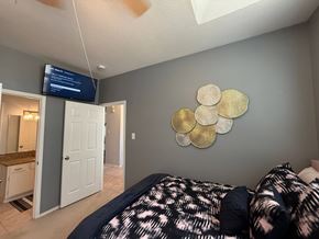 Flower Mound house for rent - A bedroom with a bed, a mirror, and a TV mounted on the wall.