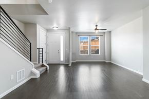 Parker house for rent - A spacious room with a staircase on the left and a window with a view of a building on the right.