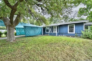 San Antonio house for rent - A blue house with a green tarp covering the windows.