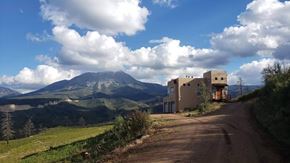 La Veta house for rent - A dirt road leads to a house with a mountain in the background.