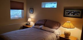La Veta house for rent - A bedroom with a bed, two lamps, and pictures on the wall.