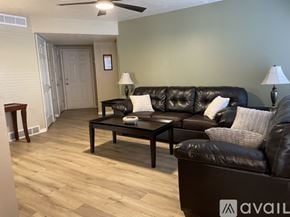 Murray condo for rent - A bed with a white and grey patterned comforter and a purple pillow is in the foreground of a room with wooden flooring and a dark wall.