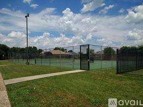 Grand Prairie house for rent - A tennis court surrounded by a fence and a walkway.