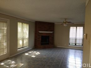 Grand Prairie house for rent - A living room with a fireplace and a ceiling fan.