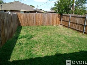 Fort Worth townhouse for rent - A backyard with a wooden fence and green grass.