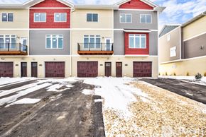 North Mankato apartment for rent - A large multi-story building with a red roof and a parking lot in front.