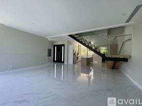 Key Biscayne house for rent - A spacious, empty room with a marble floor and a staircase in the background.