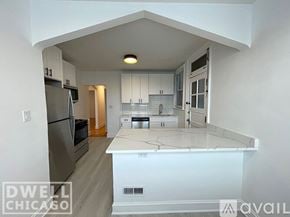 Chicago apartment for rent - A kitchen with white cabinets and a white island with a black stove top oven.