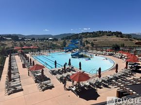 Heber City townhouse for rent - A large outdoor swimming pool surrounded by sun loungers and umbrellas.