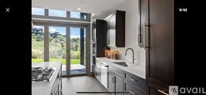 Heber City townhouse for rent - A modern kitchen with dark wood cabinets and a large window overlooking a green landscape.