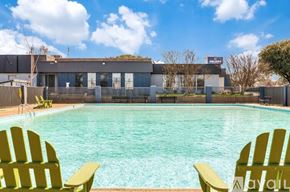 Dallas apartment for rent - Two yellow chairs are placed in front of a swimming pool.