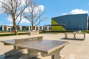 Dallas apartment for rent - A large table with the word "VALORA" on it is in the foreground of an outdoor setting with a modern building in the background.