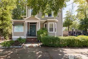 Salem condo for rent - A house with a green door and a grey facade is surrounded by greenery.