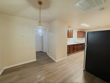 Merced house for rent - A kitchen area with a black refrigerator and wooden cabinets.