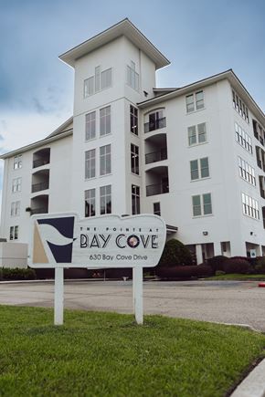Biloxi apartment for rent - A white building with a sign that says Bay Cove in front of it.