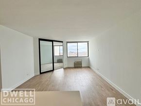 Chicago apartment for rent - A spacious room with wooden floors and a large window overlooking a cityscape.