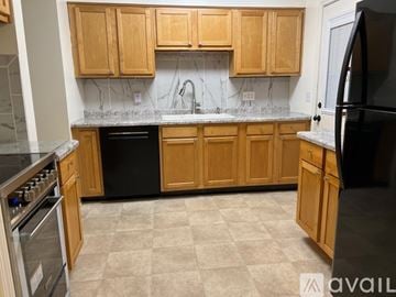 Sellersburg house for rent - A kitchen with wooden cabinets and a black refrigerator.