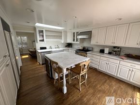 San Diego house for rent - A kitchen with white cabinets and a wooden table.