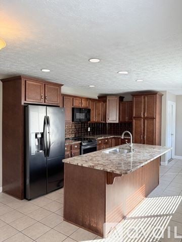 Bowling Green house for rent - A kitchen with a black refrigerator and brown cabinets.