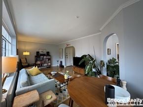 Brookline apartment for rent - A well-lit living room with a grey couch, a wooden table, and a bookshelf.