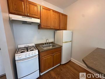 Chicago apartment for rent - A small kitchen with a white stove, sink, and refrigerator.