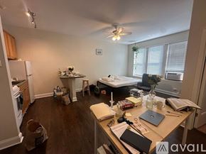 Chicago apartment for rent - A room with a bed, desk, and a fan.