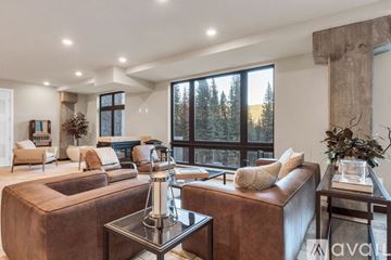 Winter Park apartment for rent - A living room with brown leather furniture and a large window overlooking a forest.
