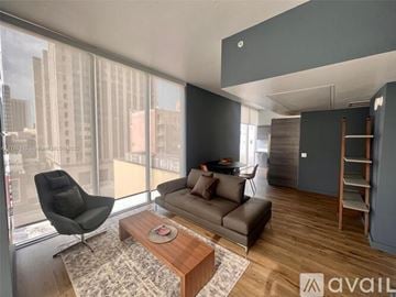 Miami condo for rent - A living room with a brown couch, a black chair, and a coffee table in front of a large window.