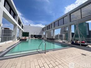 Miami condo for rent - A large outdoor pool area with a sun lounger and a person sitting on it.