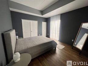 Miami condo for rent - A bedroom with a large bed, a nightstand, and a mirror.