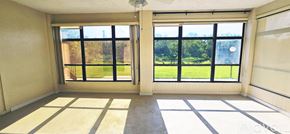 Deltona condo for rent - A room with a large window and a view of a green lawn and trees.