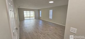 Deltona condo for rent - A spacious room with wooden flooring and a door leading to a balcony.