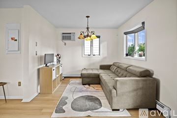 West Haven house for rent - A living room with a grey couch and a wooden cabinet.