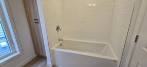 Ottawa apartment for rent - A white bathtub in a bathroom with white tiles.