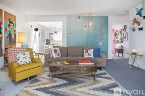 Joshua Tree house for rent - A living room with a yellow chair, a brown couch, and a rug.