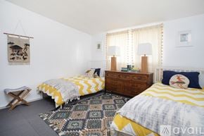 Joshua Tree house for rent - A bedroom with two beds, a bench, and a rug.