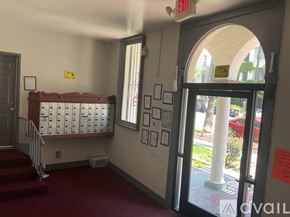 Los Angeles apartment for rent - A hallway with a red carpet, a staircase, and a bulletin board with papers on it.