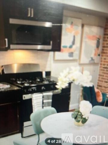 Baltimore house for rent - A kitchen with a stove and a table with a vase of flowers on it.