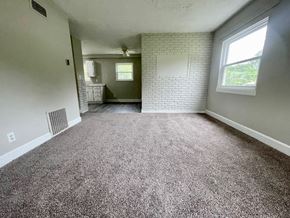 Louisville house for rent - A room with a carpeted floor and a white brick wall.