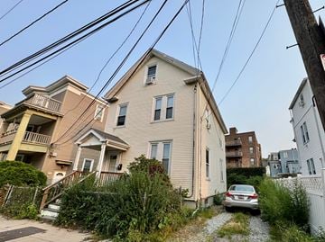 Boston house for rent - A car is parked on a gravel path in front of a house.