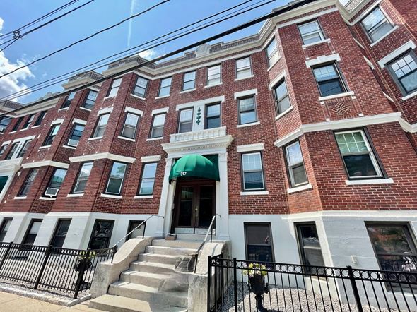 Boston apartment for rent - A red brick building with a green awning and a black fence in front.